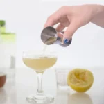 Premium dual-sided peg measurer pouring liquid accurately into a stylish cocktail glass.
