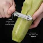 Premium stainless steel vegetable peeler effortlessly peeling zucchini with sharp rotating blade.