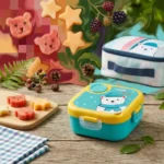 Stylish white bear lunch box displayed with snacks in picnic setting